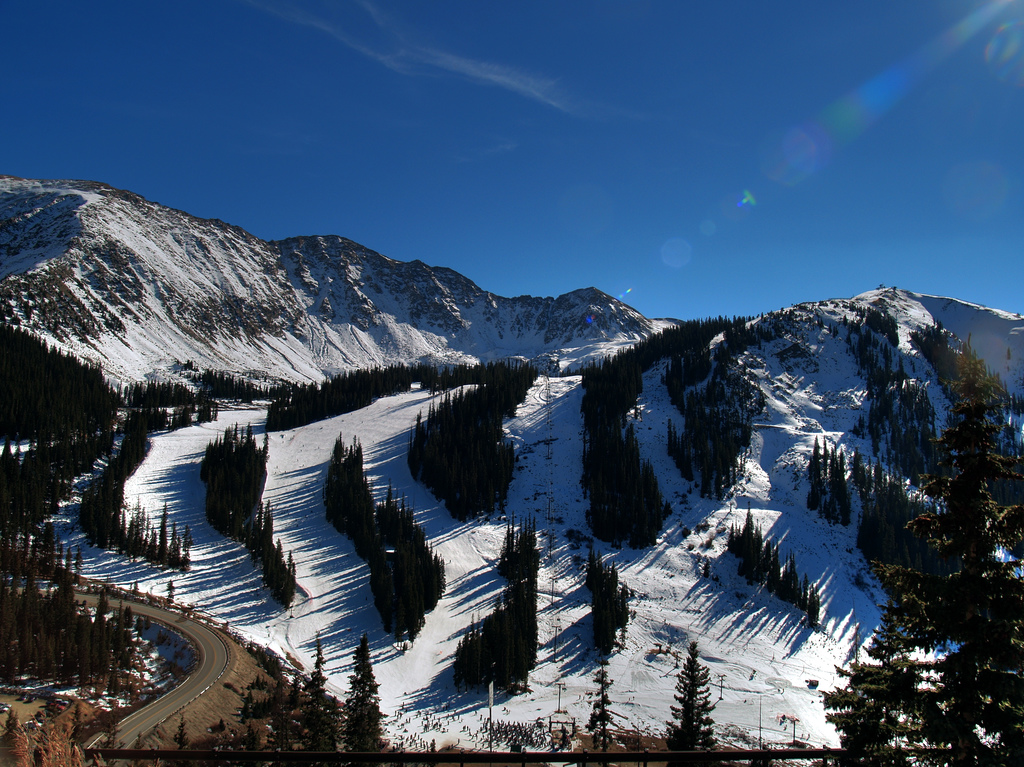 Des skieurs et snowboardeurs traversent un champ de neige ensoleillé du Colorado